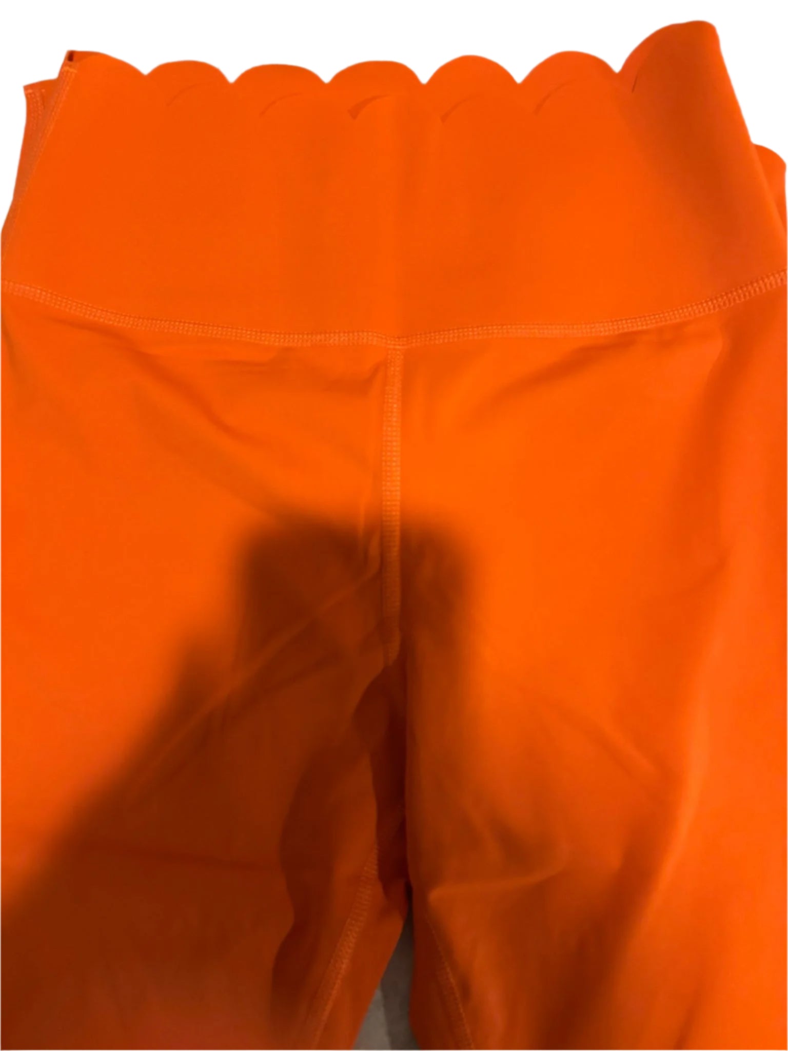 Close-up of bright orange fabric with scalloped edge